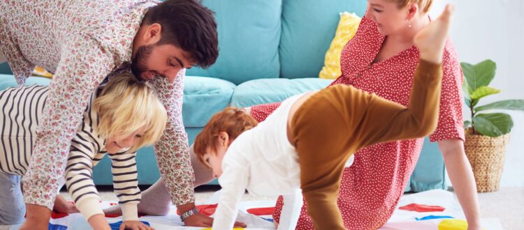 A family with young children playing Twister.