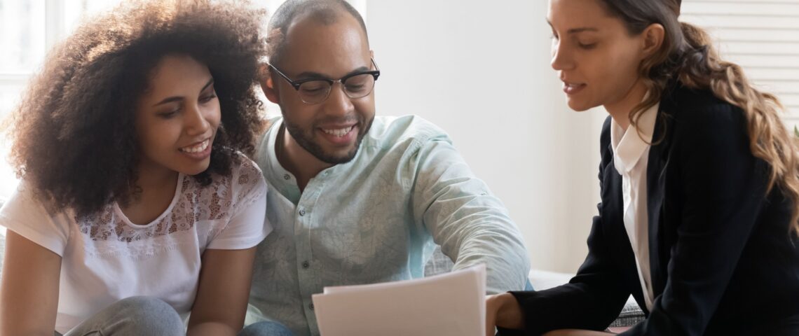 A young couple meet with their financial planner, who shows them some documents to read.