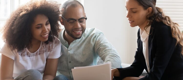 A young couple meet with their financial planner, who shows them some documents to read.