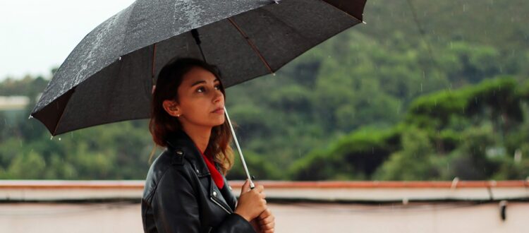 A woman shielded by an umbrella.