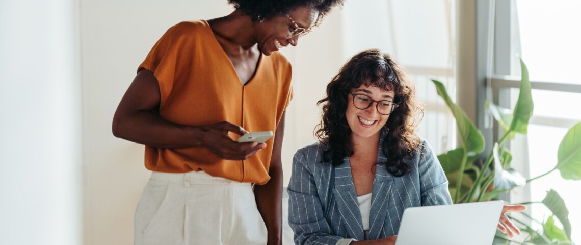 Pair of happy professional women talking in a modern office setting
