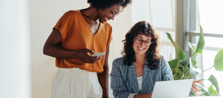 Pair of happy professional women talking in a modern office setting