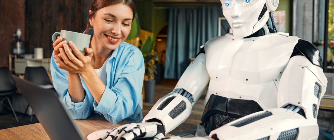 Young woman with a cup of coffee watching while a robot works at a laptop