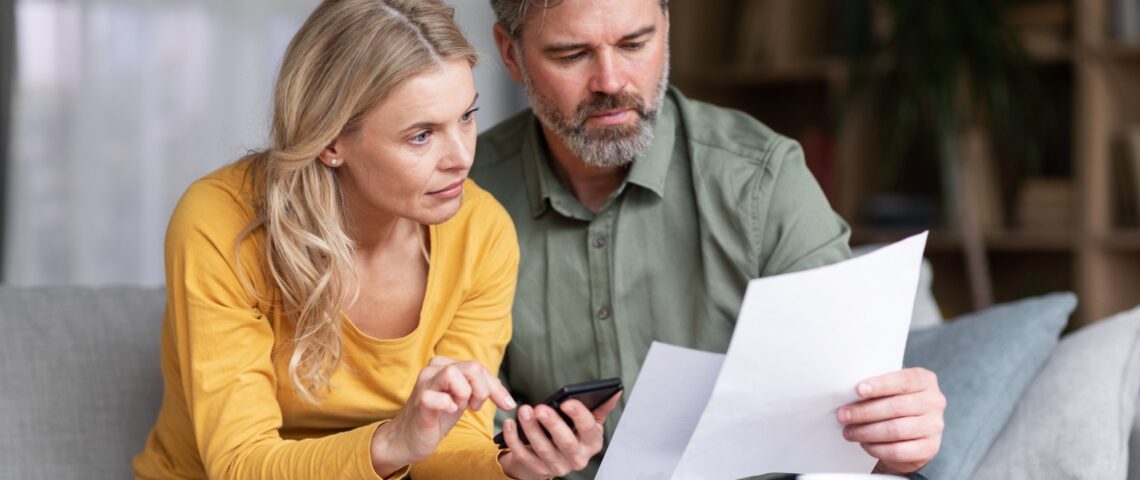 Couple compares two documents while typing on a phone