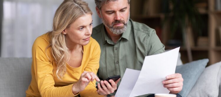 Couple compares two documents while typing on a phone