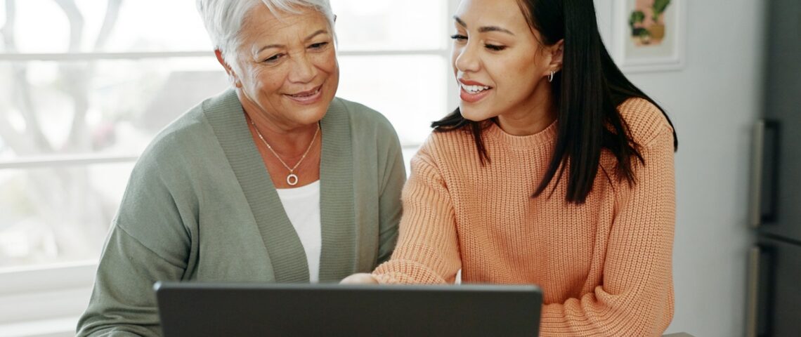 Senior mum and adult daughter looking at a laptop