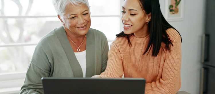 Senior mum and adult daughter looking at a laptop