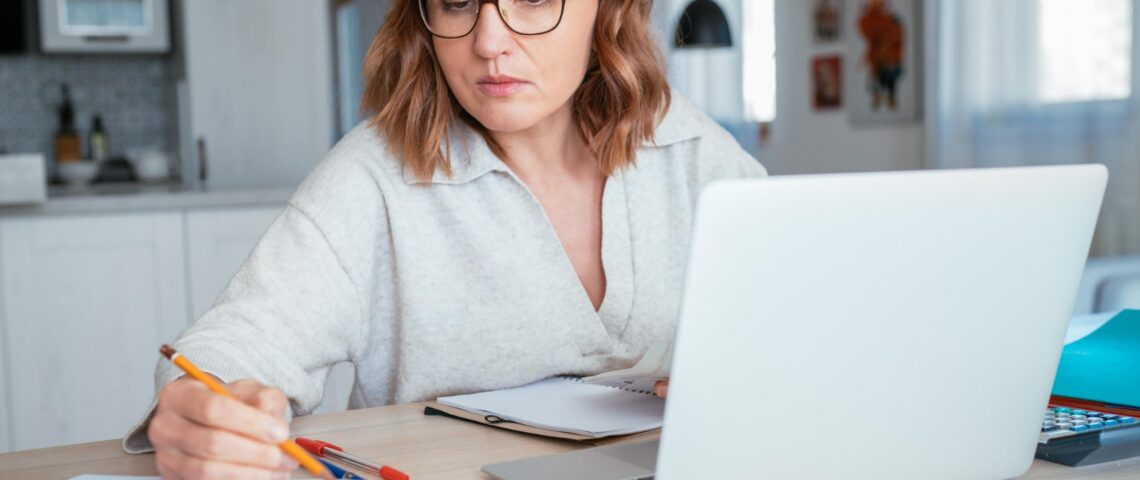 Woman with laptop looking at her notebook