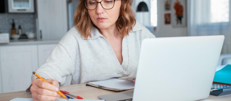 Woman with laptop looking at her notebook