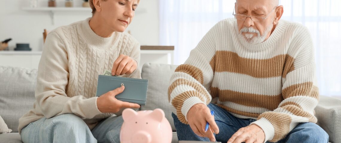 Middle-aged couple planning their finances with a calculator, wallet, and piggy bank.