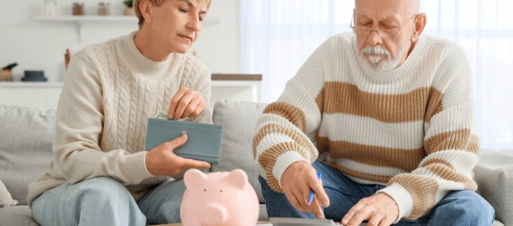 Middle-aged couple planning their finances with a calculator, wallet, and piggy bank.