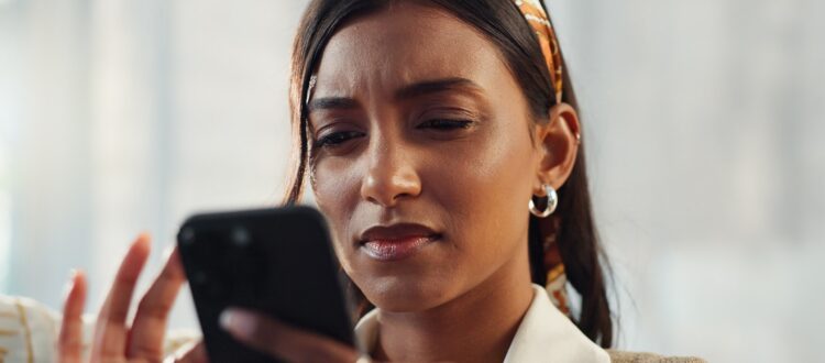 A woman frowning at her phone
