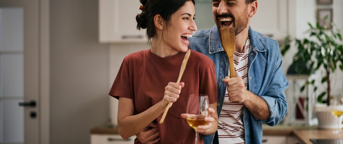 Happy couple singing and having fun while preparing a meal