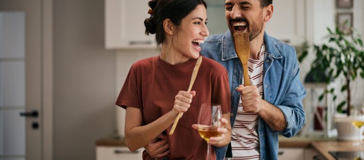 Happy couple singing and having fun while preparing a meal