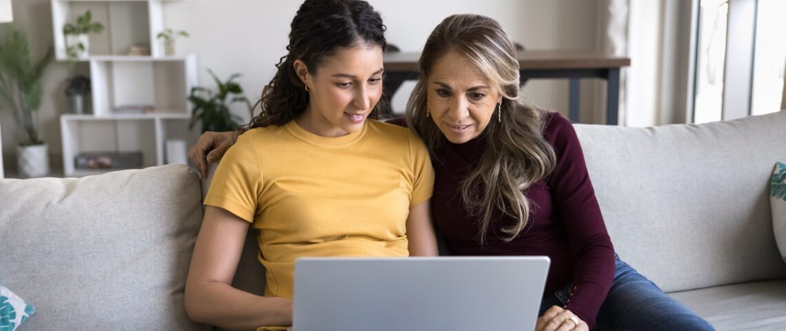 Young adult with mother looking at laptop screen in living room
