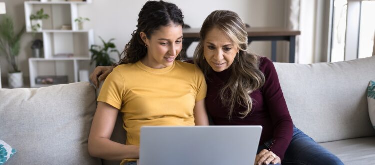Young adult with mother looking at laptop screen in living room