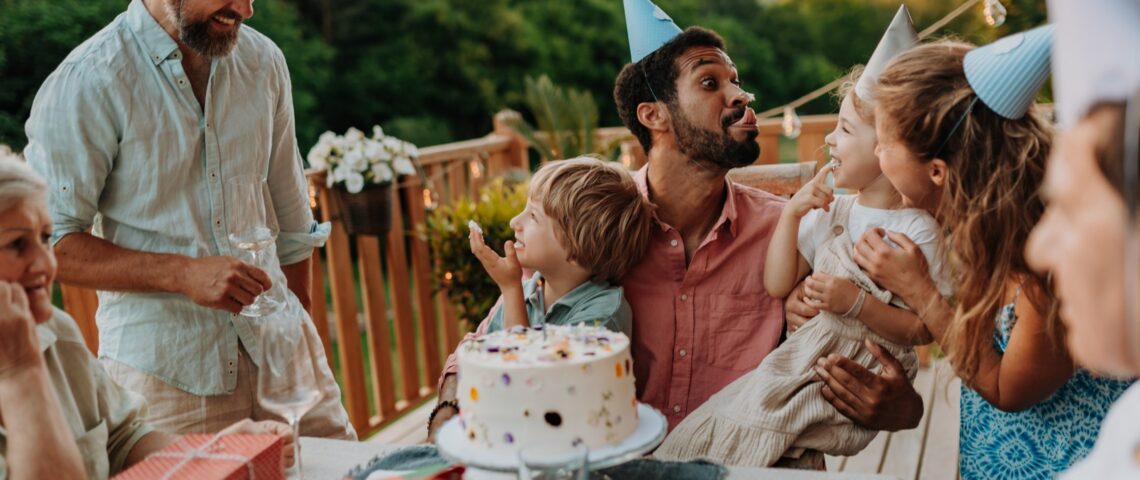 Multi-generational family celebrating a birthday on deck overlooking garden