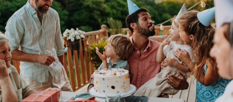 Multi-generational family celebrating a birthday on deck overlooking garden